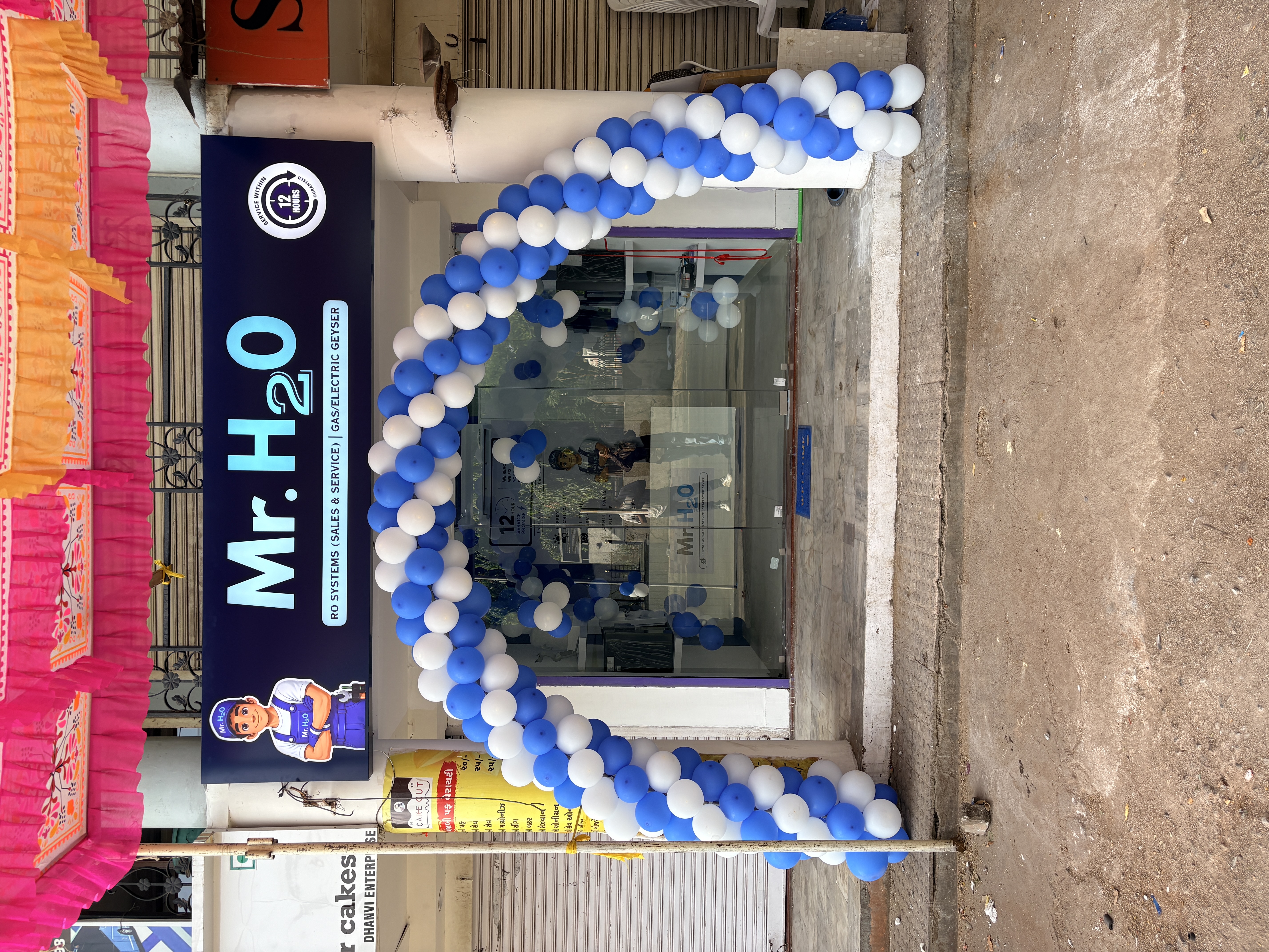 Mr. H2O franchise storefront with branded signage reading RO Systems Sales and Service, Gas/Electric Geyser, decorated for grand opening