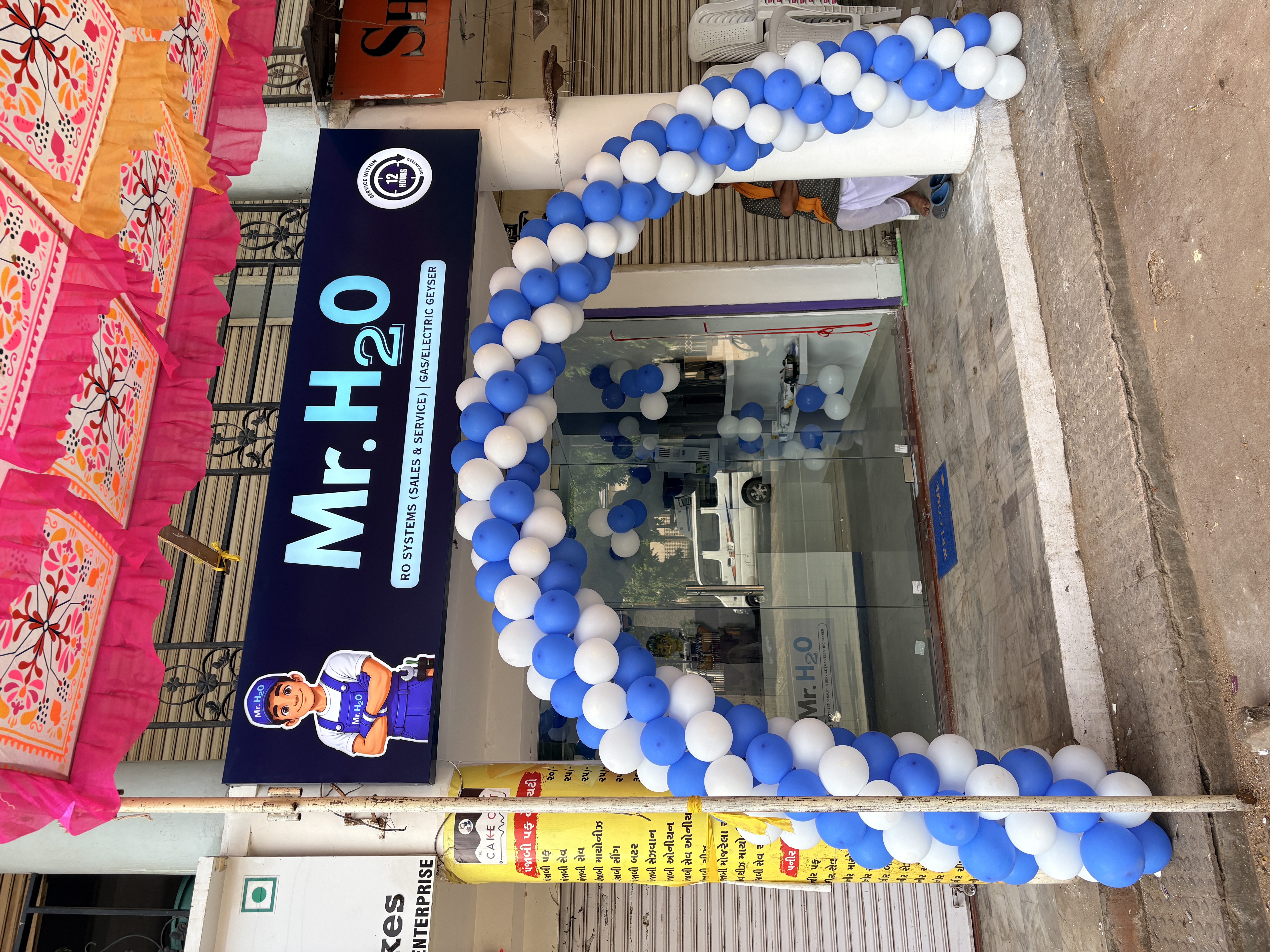 Mr. H2O franchise storefront grand opening with blue and white balloon arch decoration